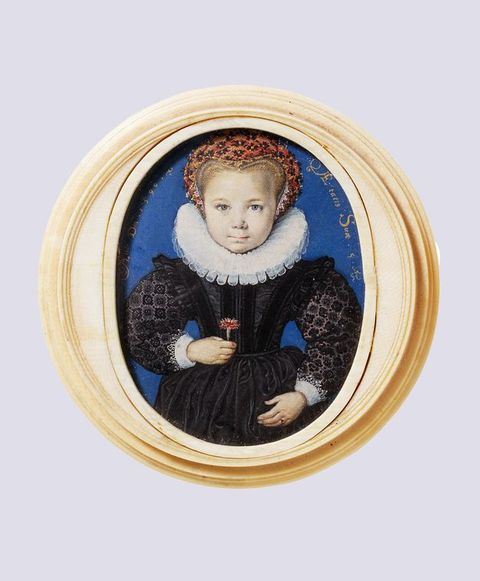 Watercolour. Set in a carved ivory frame, a young, smooth-cheeked, pale-skinned girl looks squarely out at us with blue eyes. Her blond hair is mostly covered in a red, black, and gold headdress, and she wears a wide, white pleated ruff and a black dress. She holds a carnation in front of her bodice.