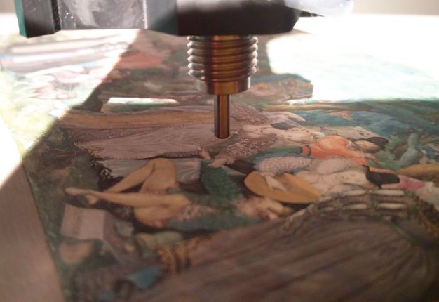 The tip of a probe hovers near the surface of a colourful work of art.